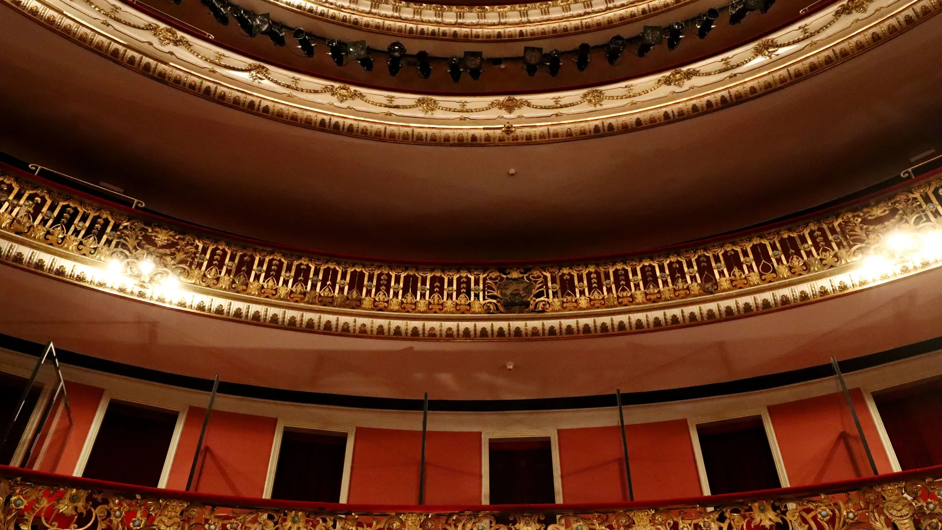 Gilded balcony tiers and stage lighting inside a theatre auditorium